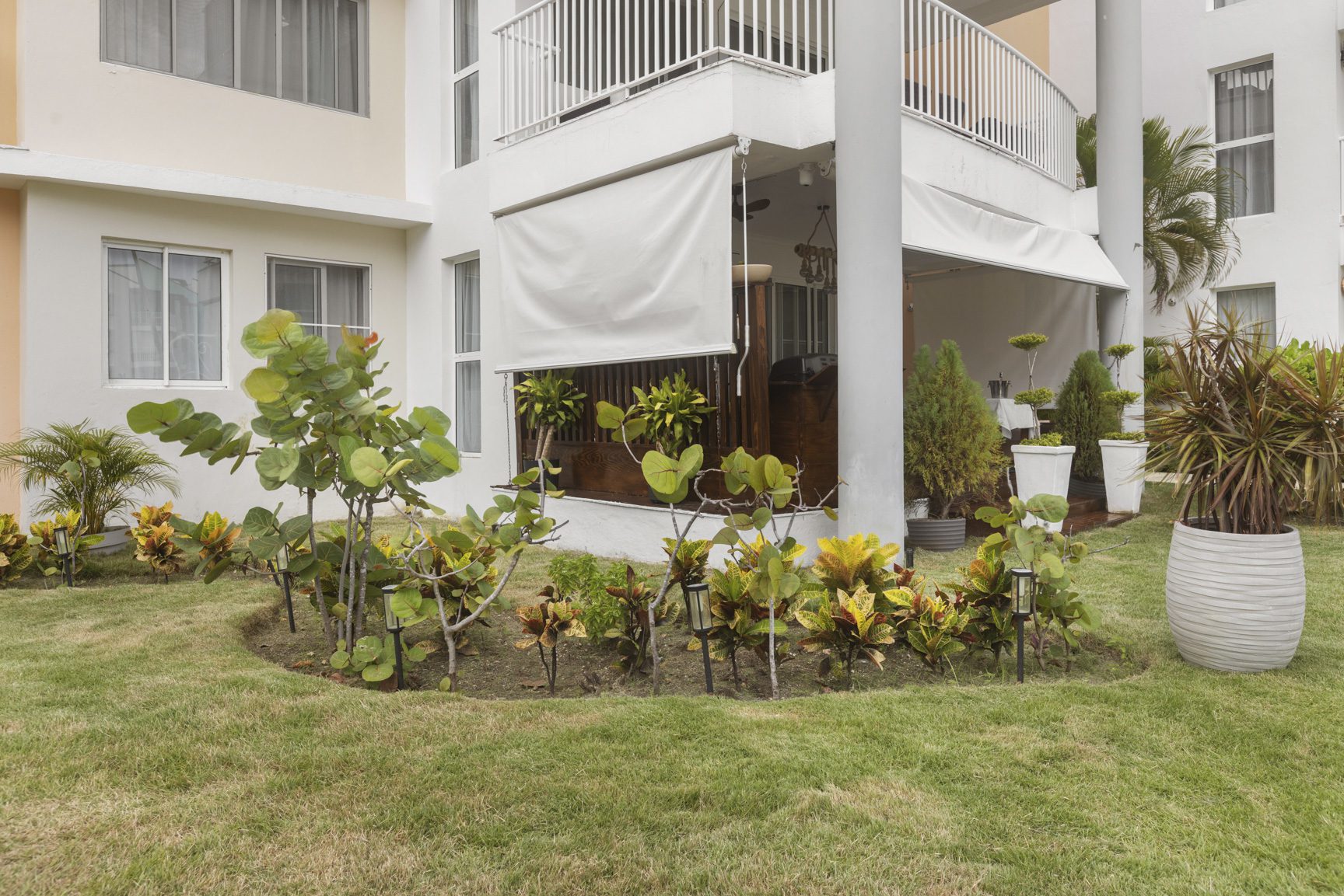 buyDRproperty Landscaped garden with tropical plants and modern building exterior. Sosua Real Estate