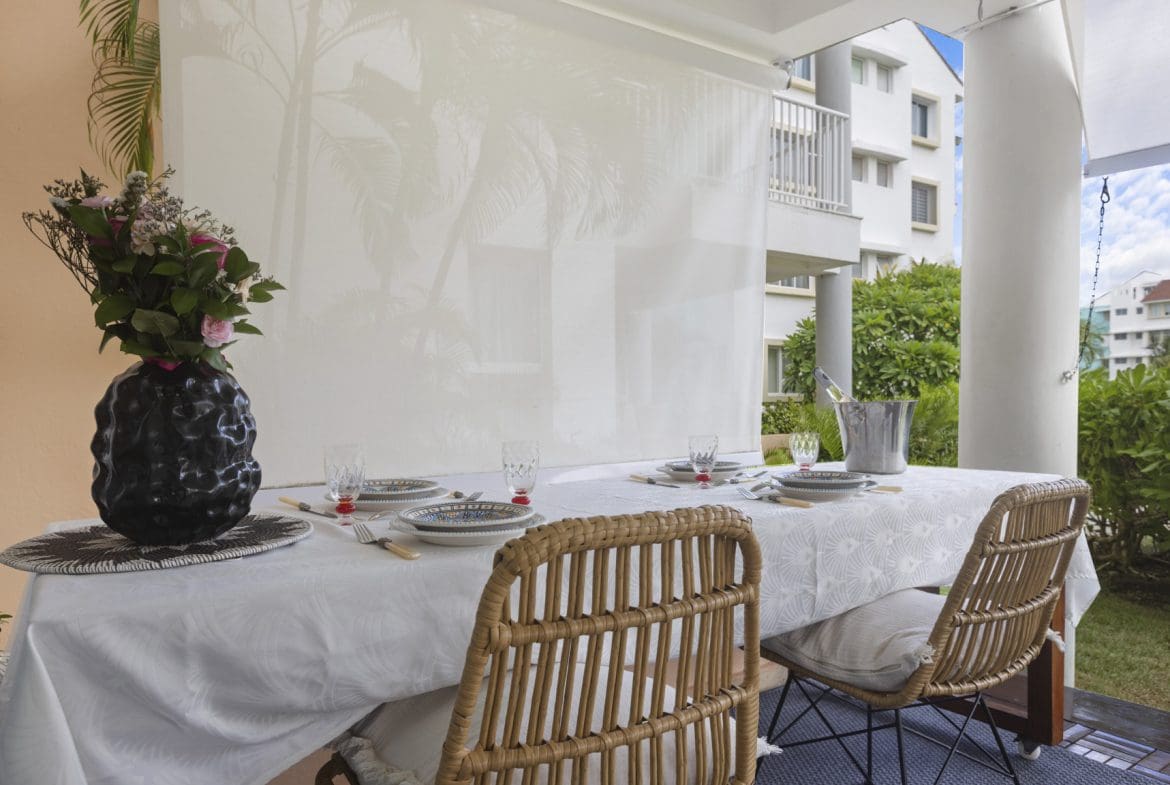 buyDRproperty Outdoor dining table set with plates, cutlery, and flowers. Sosua Real Estate