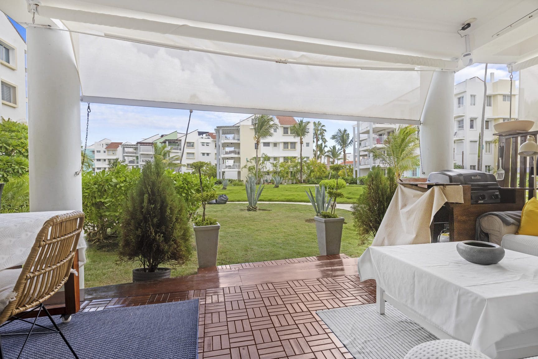 buyDRproperty Patio view of a green lawn, landscaping, and apartments in a tropical resort. Sosua Real Estate
