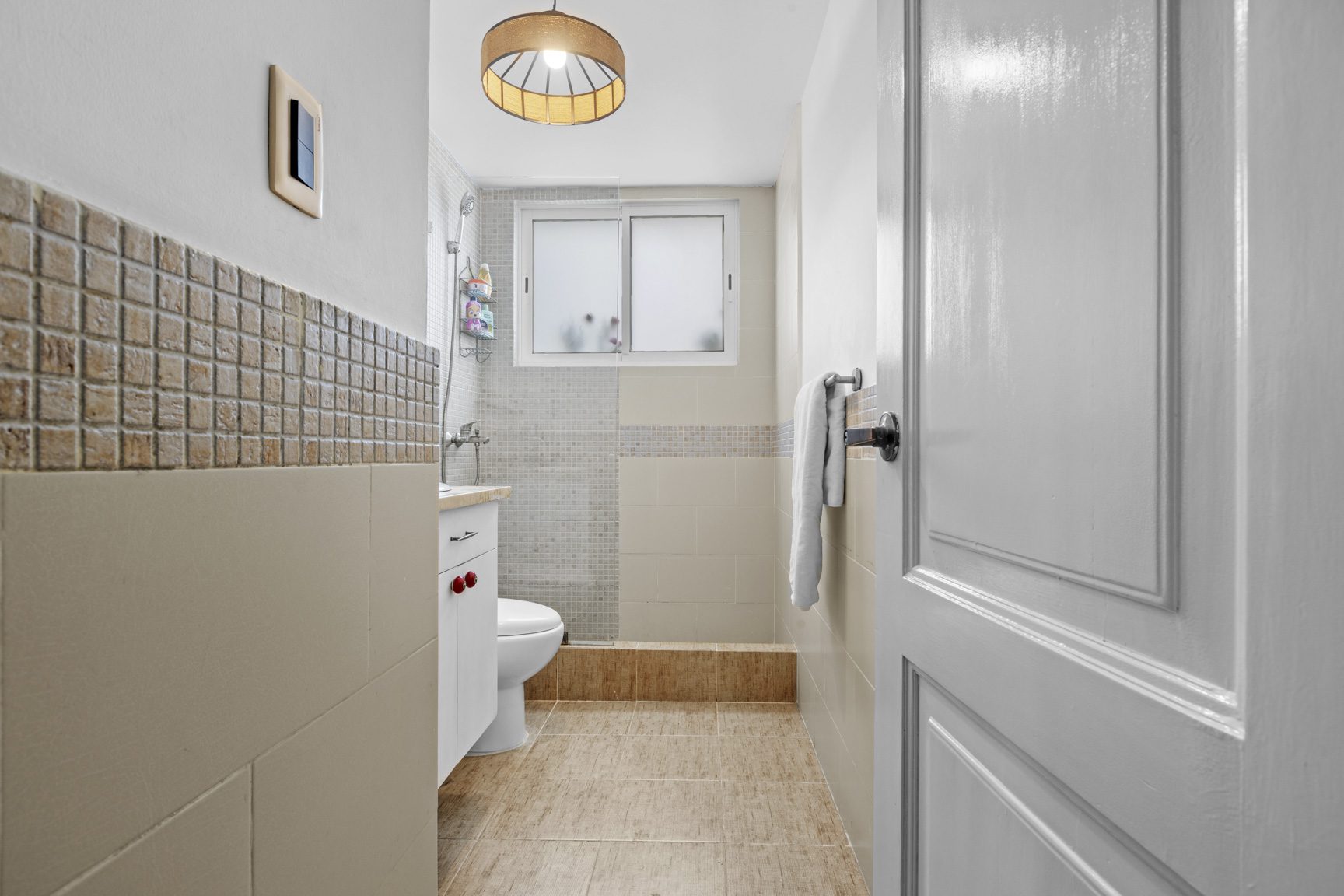 buyDRproperty Small bathroom with beige and brown tile, white toilet and vanity. Sosua Real Estate