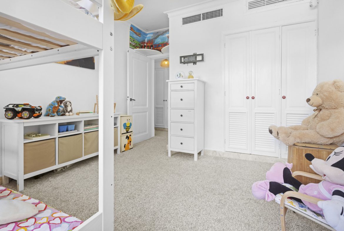 buyDRproperty Bright children's room with a bunk bed, white furniture, and plush toys on a beige carpet. Sosua Real Estate