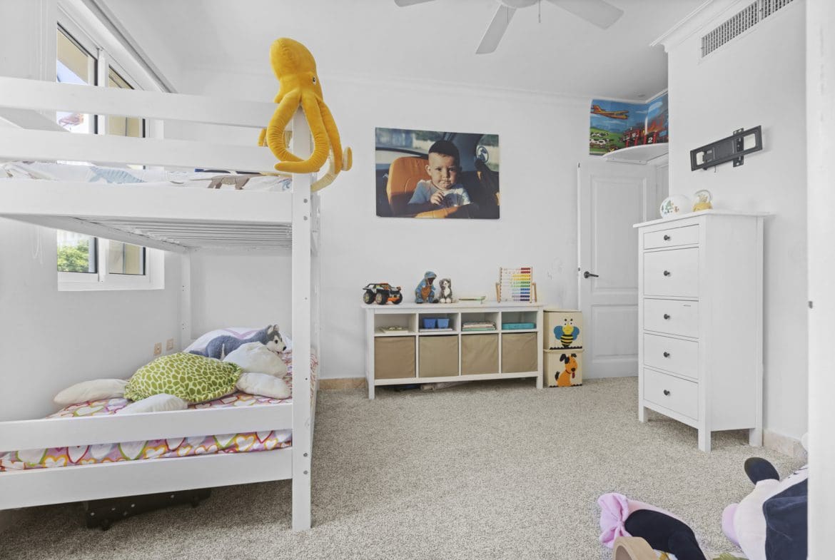 buyDRproperty White kids' room with bunk bed, toys, and a child's portrait. Sosua Real Estate