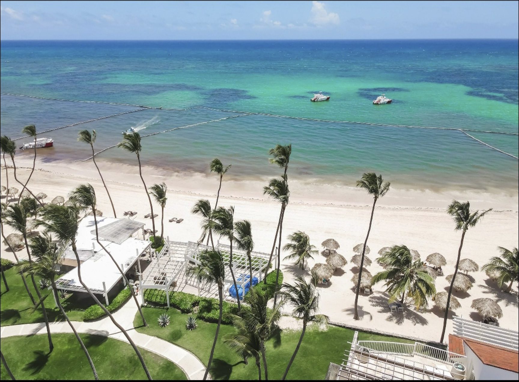 buyDRproperty Aerial view of a Caribbean beach resort with palm trees and turquoise water. Sosua Real Estate