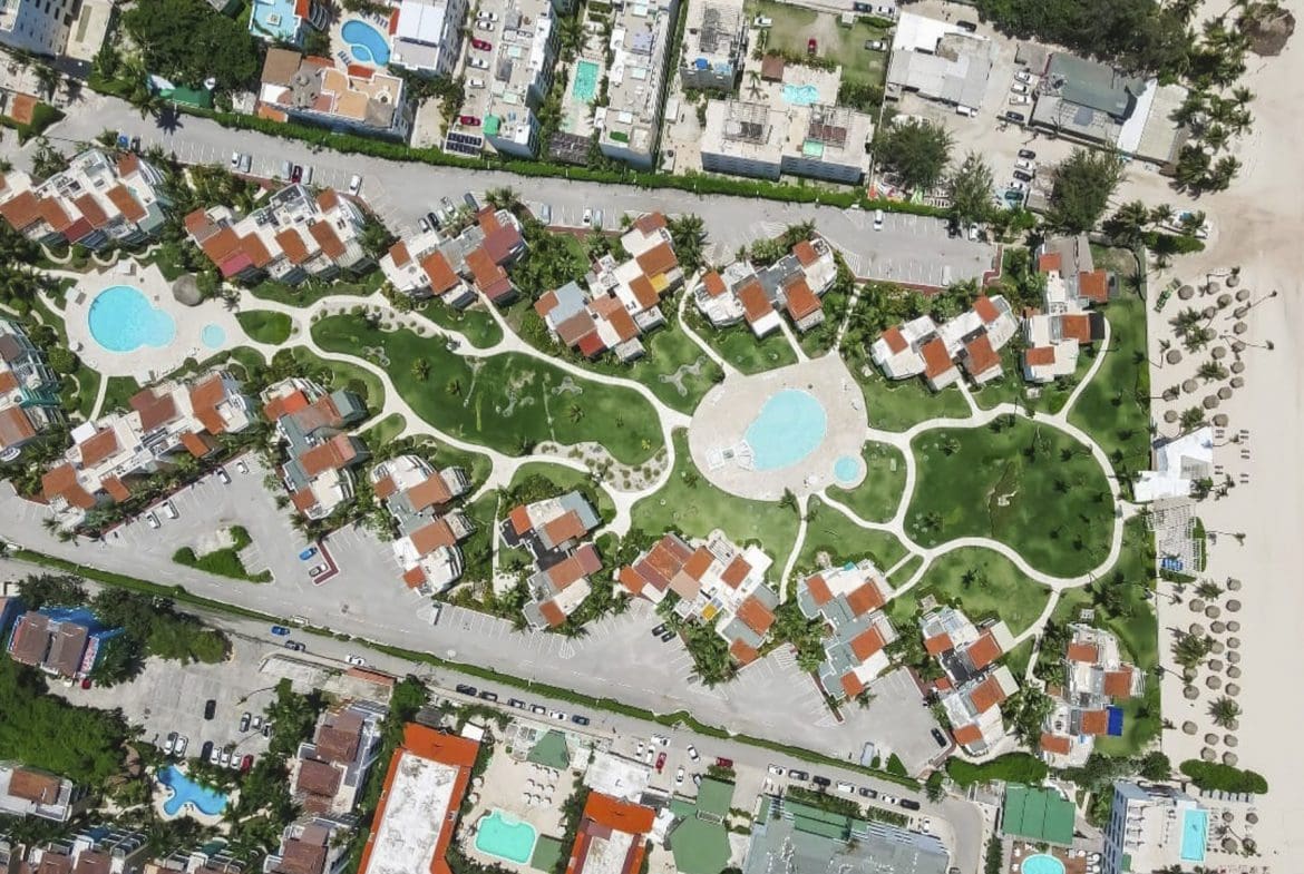 buyDRproperty Aerial view of a tropical resort with pools, green lawns, and beach access. Sosua Real Estate