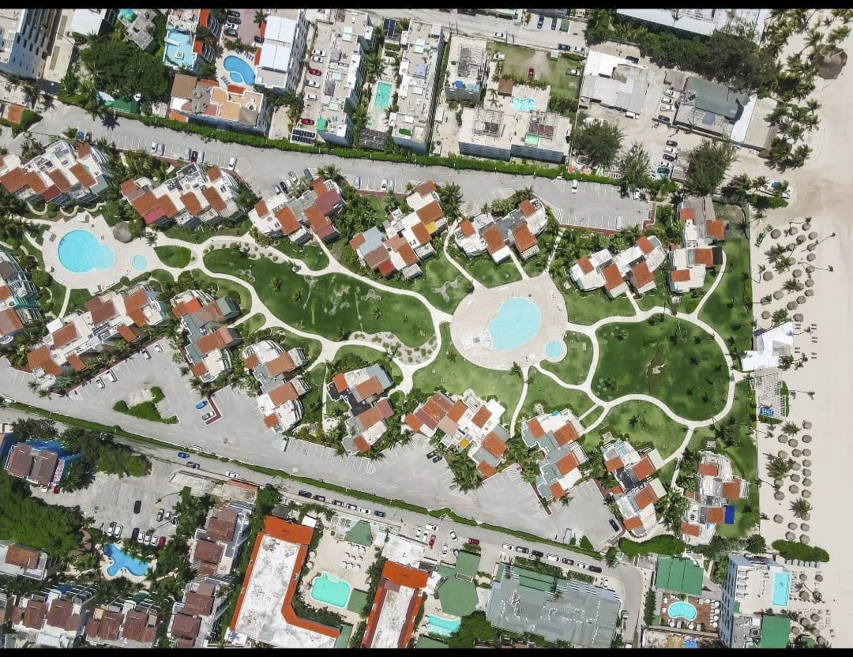 buyDRproperty Aerial view of a tropical resort with pools, green lawns, and beach access. Sosua Real Estate