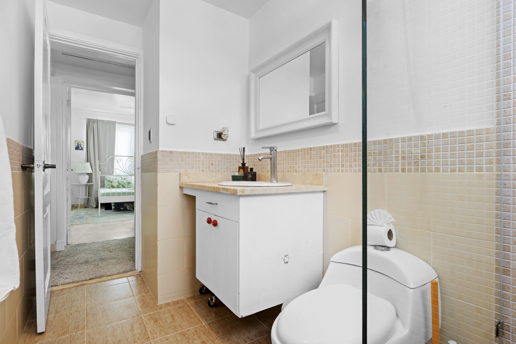 buyDRproperty Modern bathroom with beige tiles, white sink, silver faucet, and white toilet Sosua Real Estate