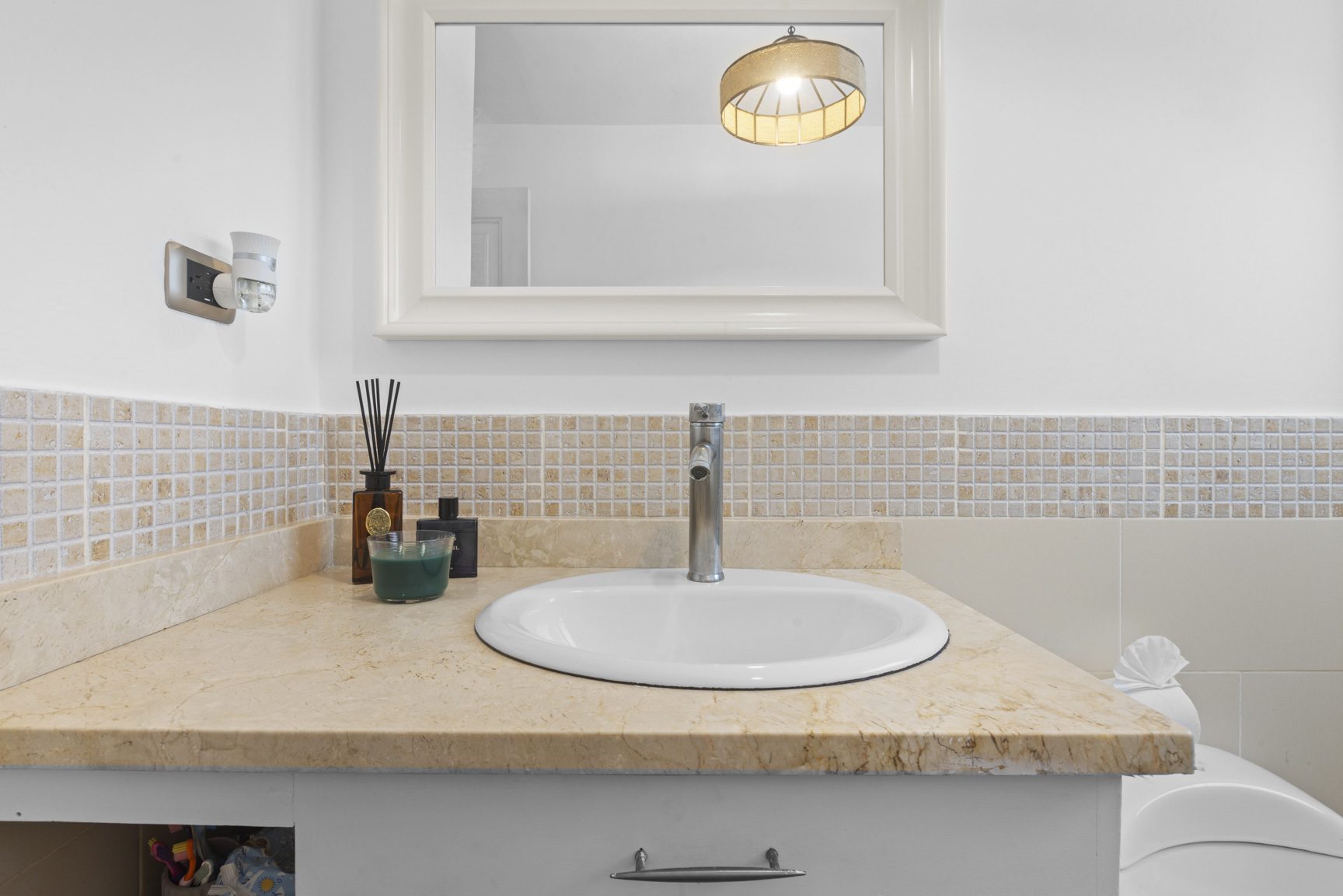 buyDRproperty Bathroom vanity with a white sink, beige countertop, and decorative mirror. Sosua Real Estate
