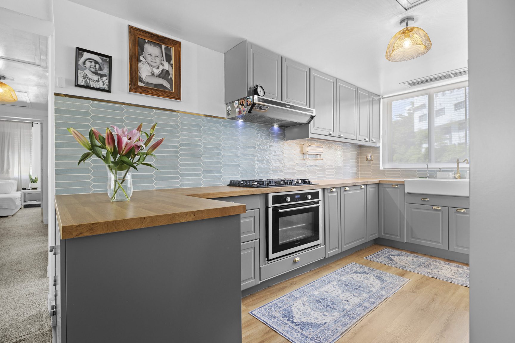 buyDRproperty Modern gray kitchen with wood countertops, blue tile backsplash, oven, and farmhouse sink. Sosua Real Estate