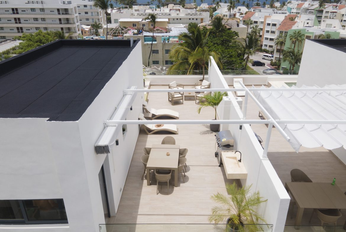 buyDRproperty Rooftop terrace with modern outdoor furniture, dining area, lounge chairs, and ocean view. Sosua Real Estate