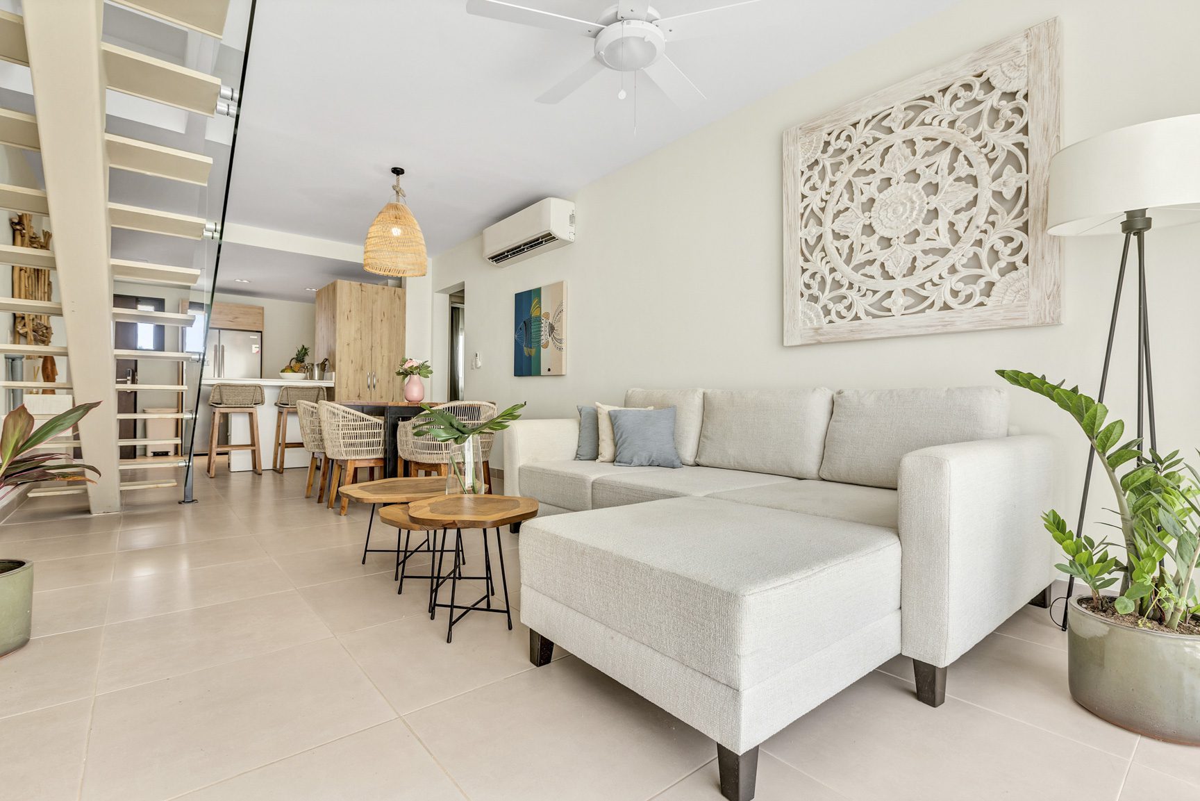 buyDRproperty Bright living room with white sofa, wooden coffee tables, and open staircase, creating a modern, airy space. Sosua Real Estate