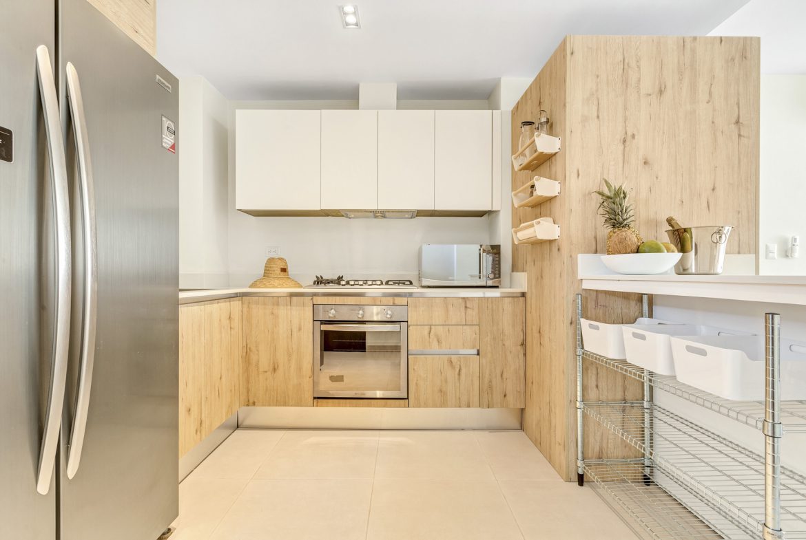 buyDRproperty Modern kitchen with stainless steel appliances, light wood cabinets, and white countertops. Sosua Real Estate