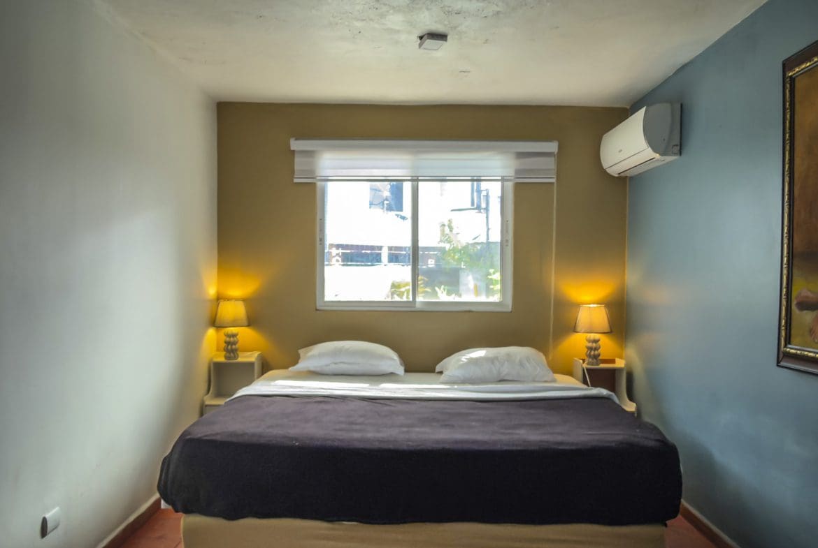 buyDRproperty Cozy bedroom with a king-sized bed, bedside lamps, and air conditioning unit on the wall. Sosua Real Estate