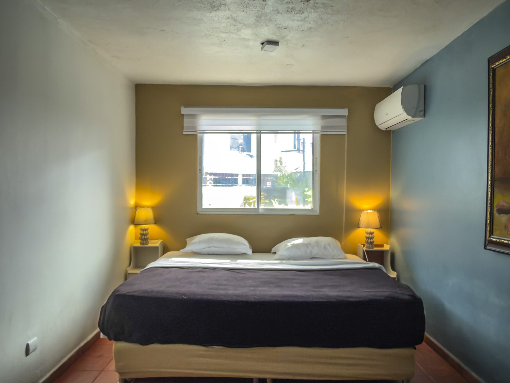 buyDRproperty Cozy bedroom with a king-sized bed, bedside lamps, and air conditioning unit on the wall. Sosua Real Estate