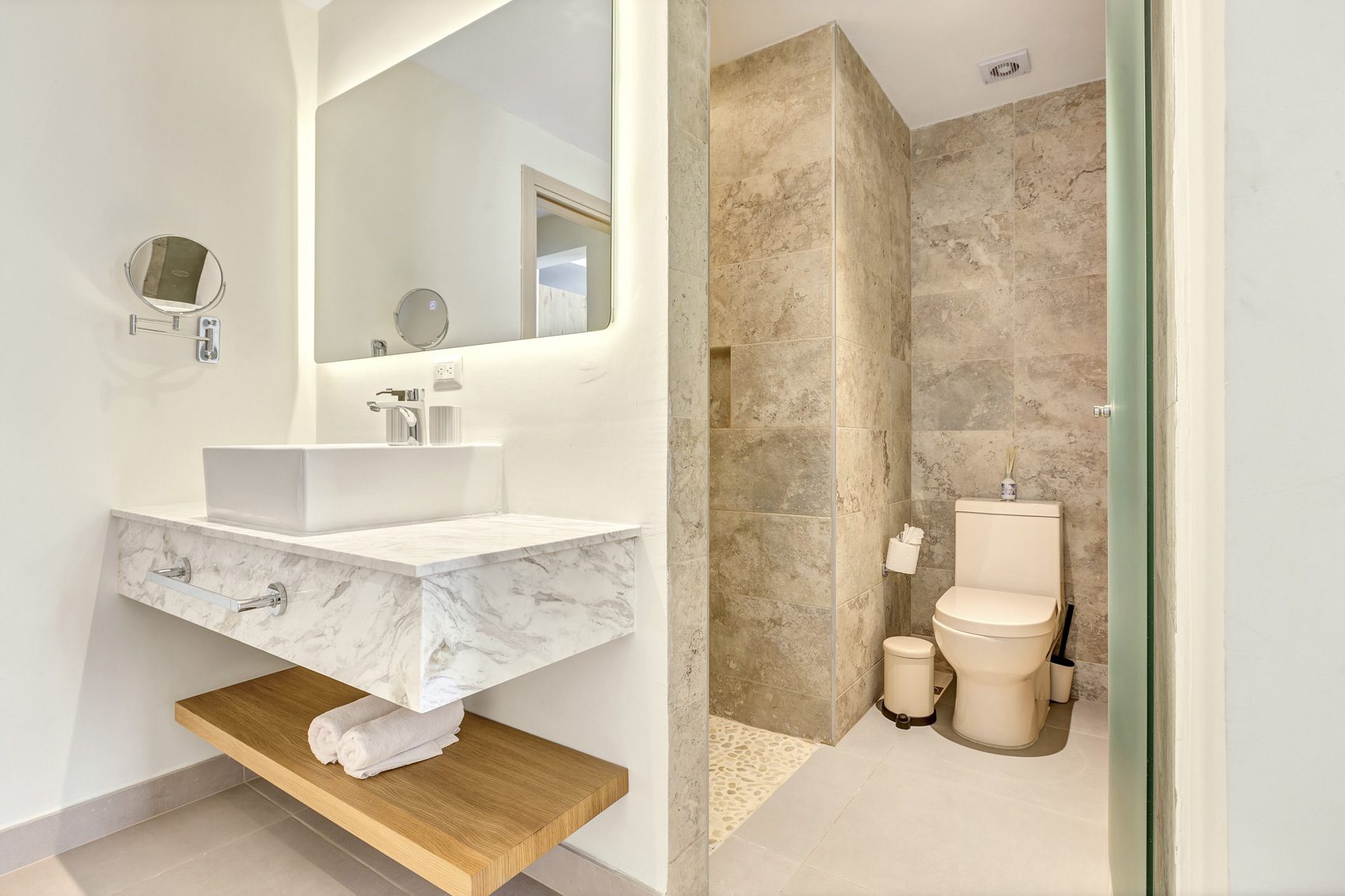 buyDRproperty Modern bathroom with floating vanity, marble countertop, and tan tile shower with toilet Sosua Real Estate