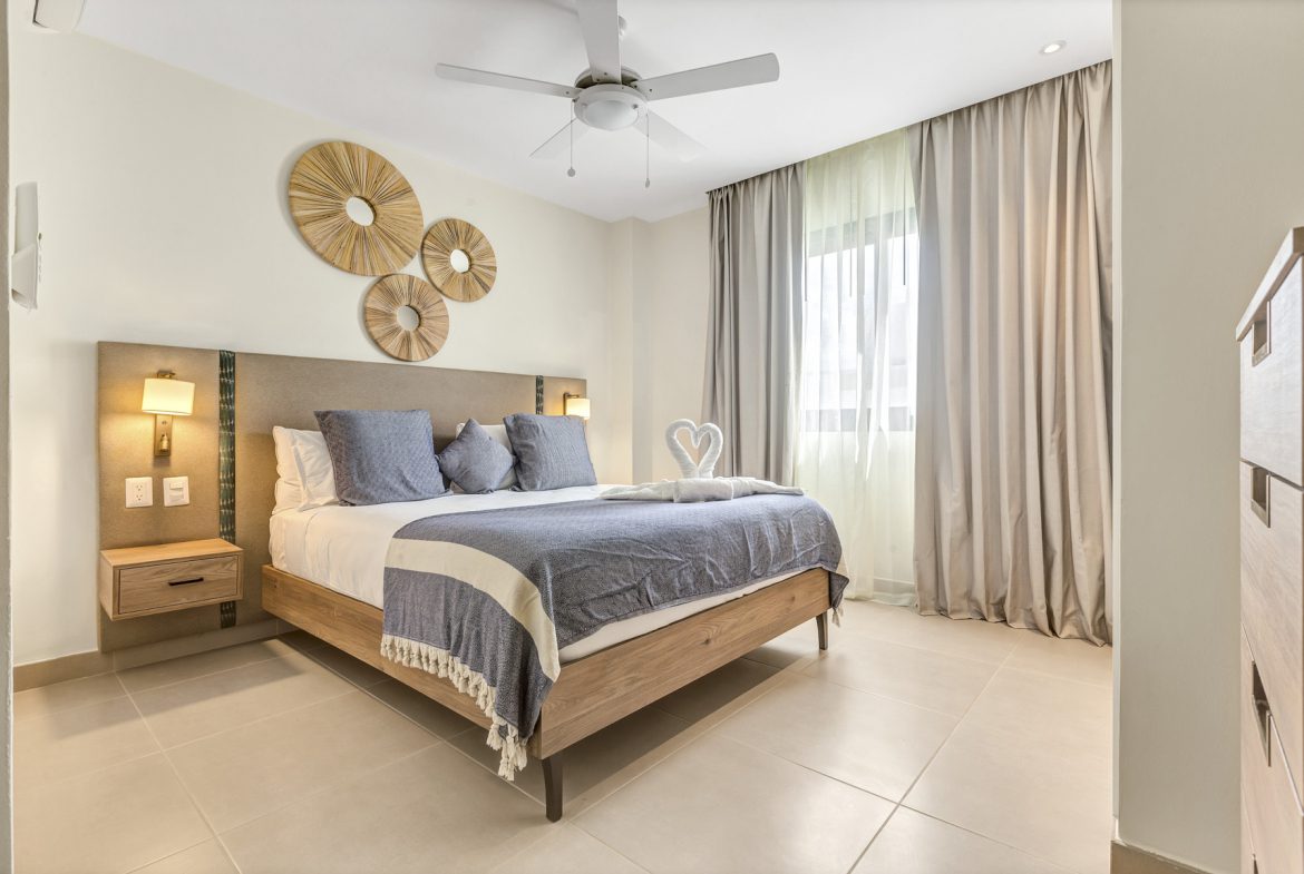 buyDRproperty Modern bedroom with king bed, woven wall art, and swan towel display. Sosua Real Estate