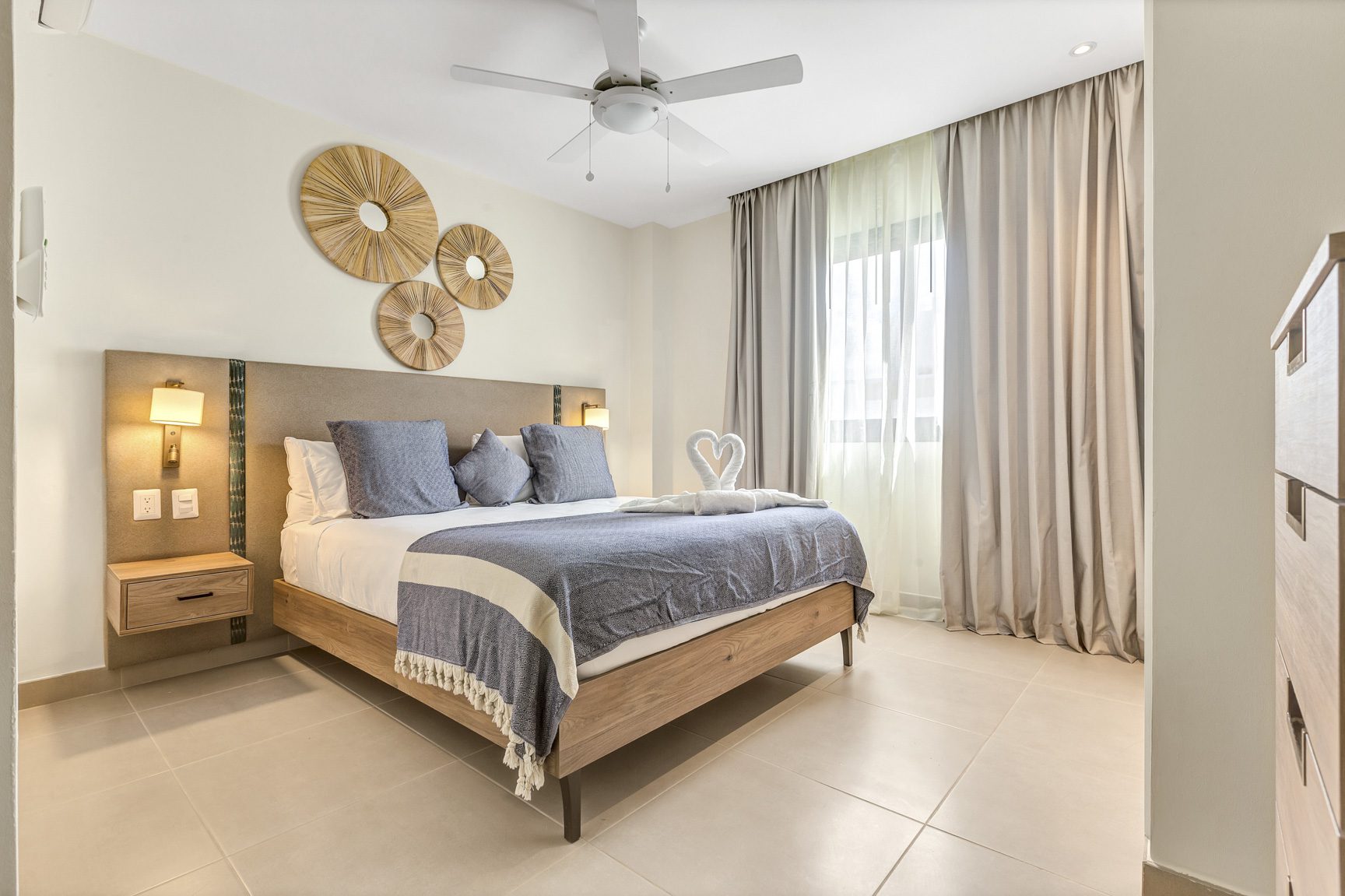 buyDRproperty Modern bedroom with king bed, woven wall art, and swan towel display. Sosua Real Estate