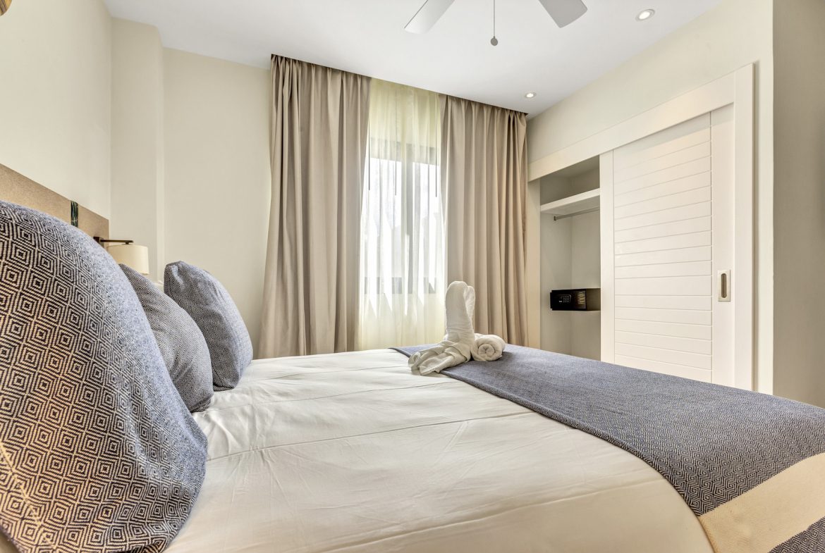 buyDRproperty Bright bedroom with white linens, blue accents, and a closet with sliding doors. Sosua Real Estate