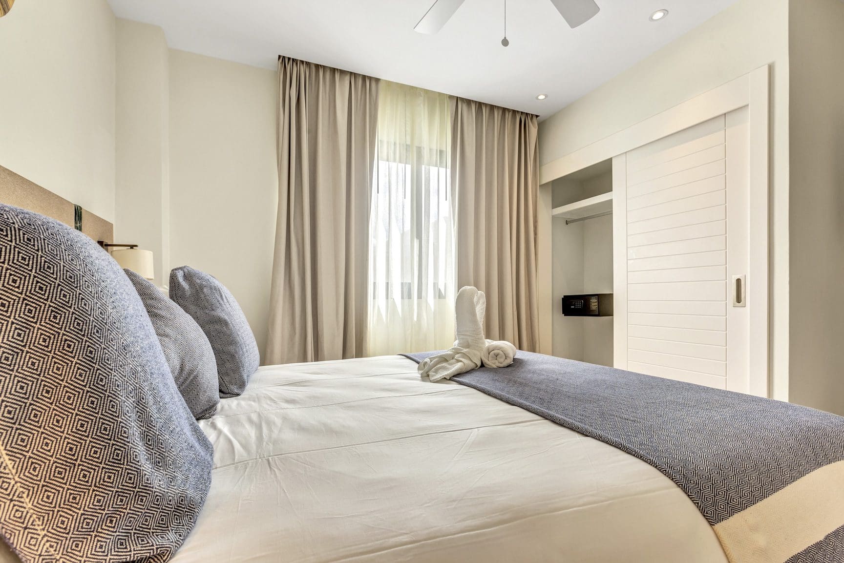buyDRproperty Bright bedroom with white linens, blue accents, and a closet with sliding doors. Sosua Real Estate