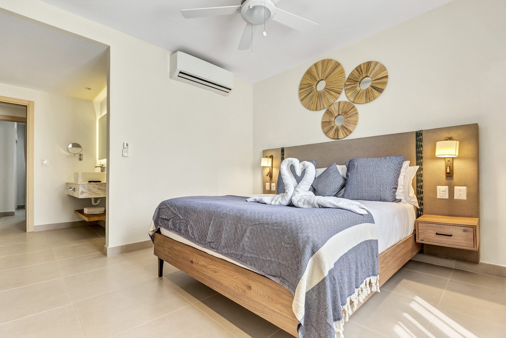 buyDRproperty Hotel bedroom with king-size bed, swan towel art, and modern bathroom entrance. Sosua Real Estate