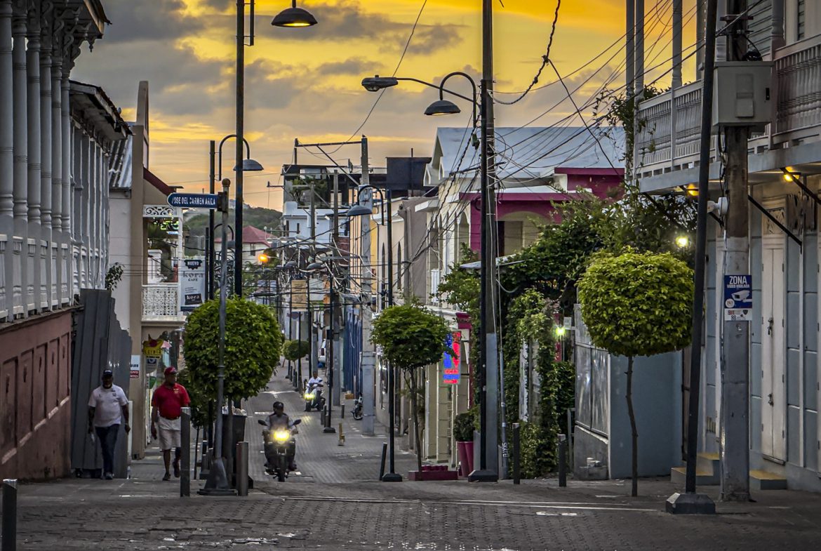 buyDRproperty Person reading book on bench in relaxing park setting. Sosua Real Estate