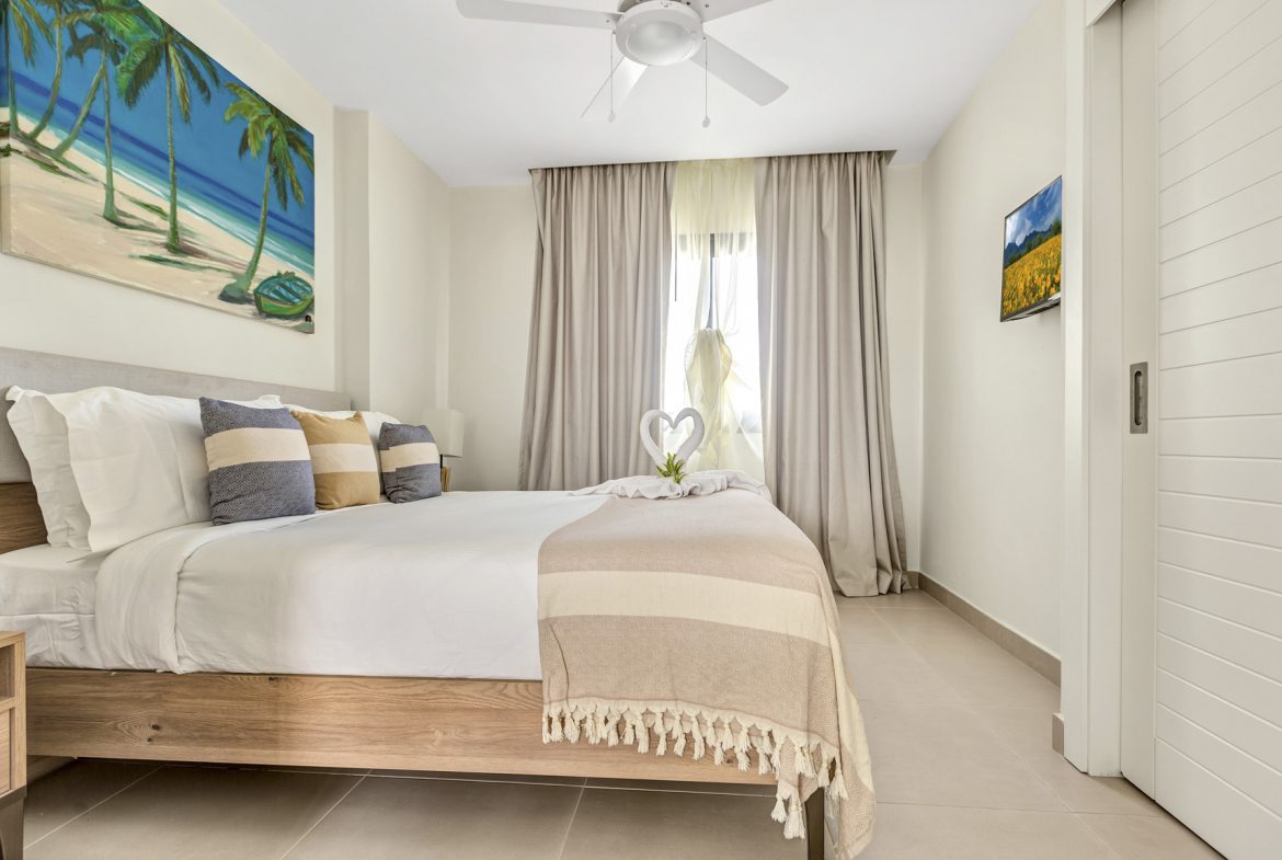 buyDRproperty Bright bedroom with king bed, beach painting, and white decor. Modern interior design. Sosua Real Estate
