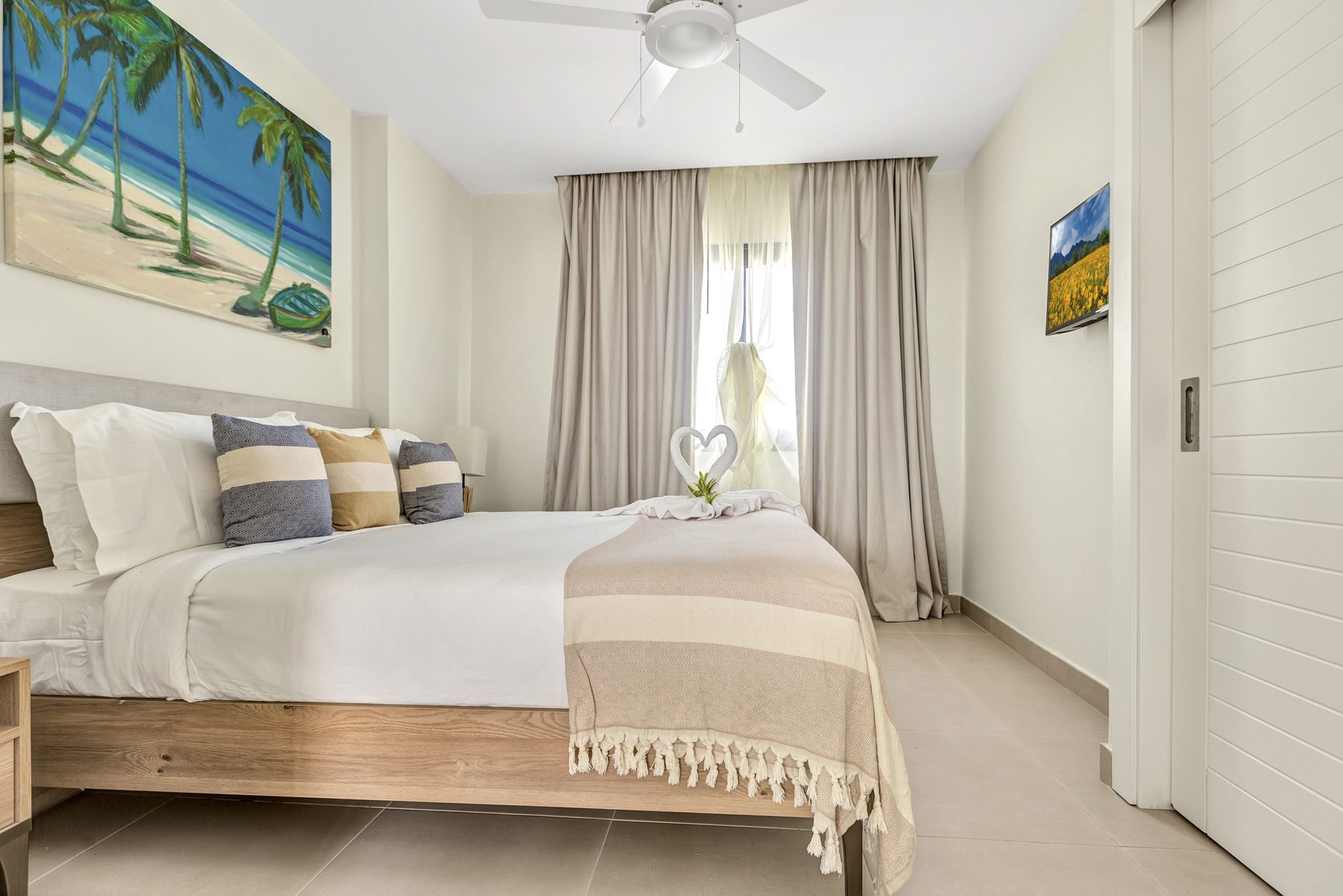 buyDRproperty Bright bedroom with king bed, beach painting, and white decor. Modern interior design. Sosua Real Estate