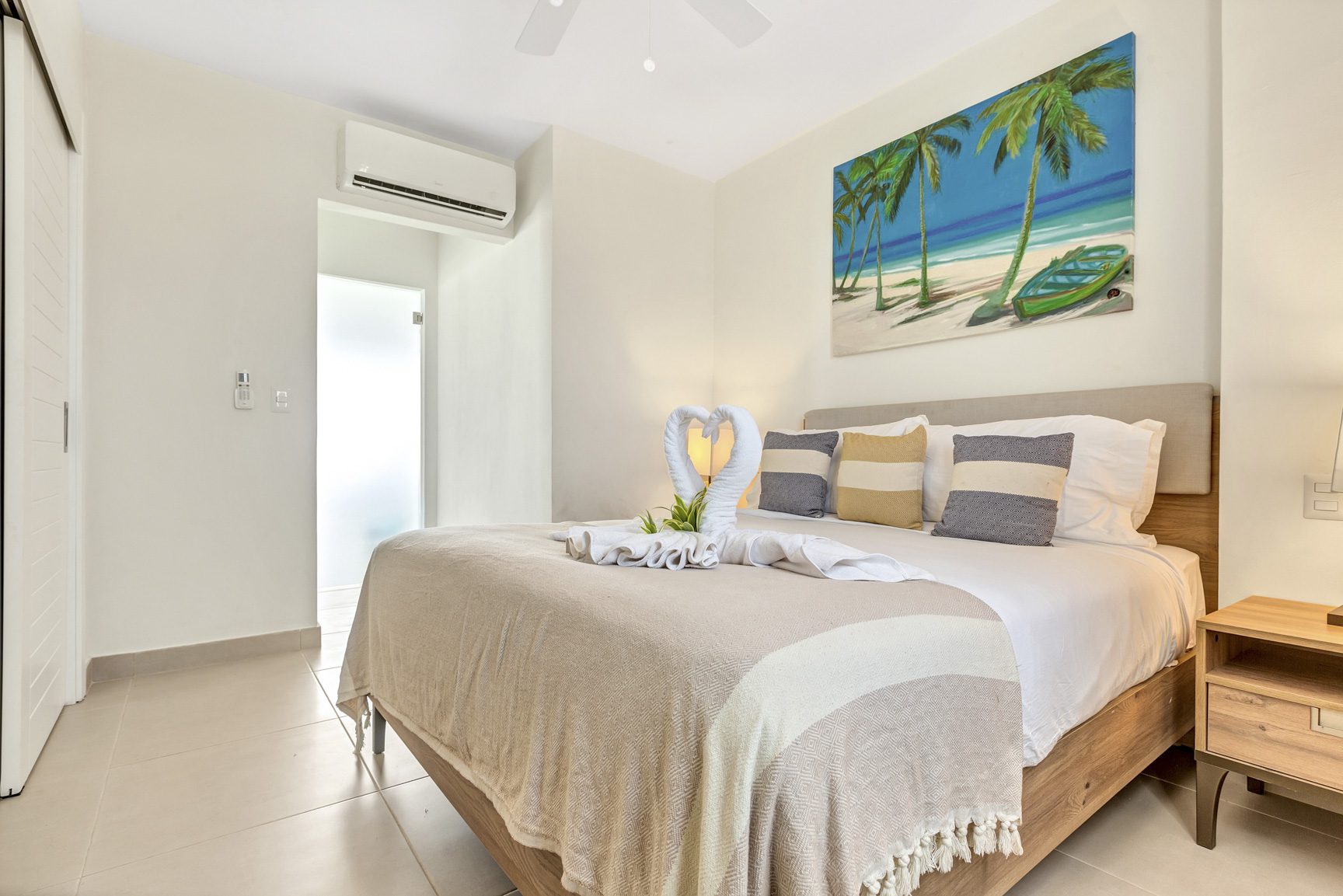 buyDRproperty Bright bedroom with swan towels, palm tree art, and a beach vibe. Sosua Real Estate
