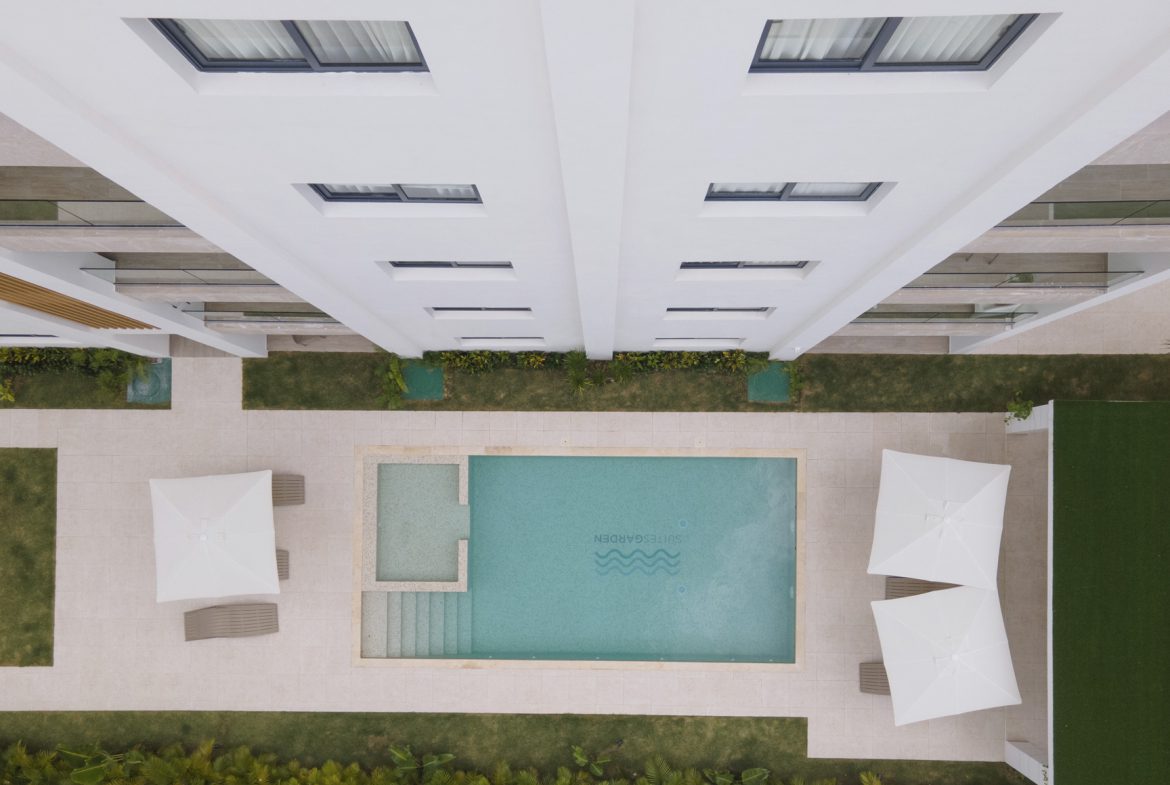 buyDRproperty Overhead view of a modern building with a pool, lounge chairs, and umbrellas. Sosua Real Estate