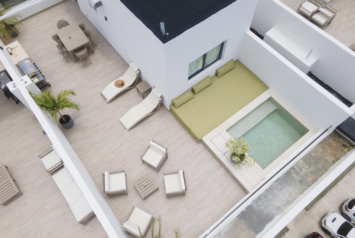 buyDRproperty Rooftop patio with pool, dining, lounge chairs, and modern design elements. Sosua Real Estate