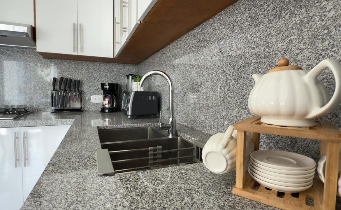 buyDRproperty Modern kitchen with granite countertops, white cabinets, and tea set. Sosua Real Estate