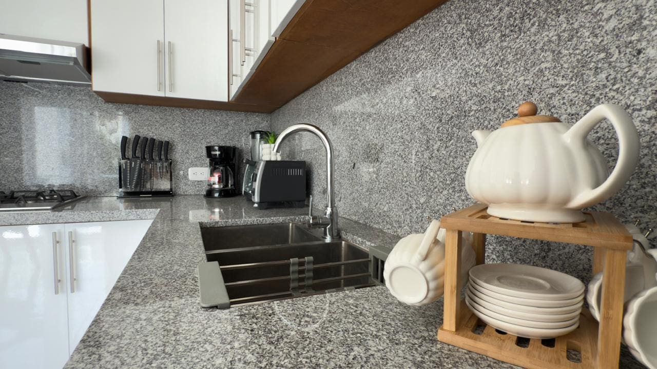 buyDRproperty Modern kitchen with granite countertops, white cabinets, and tea set. Sosua Real Estate