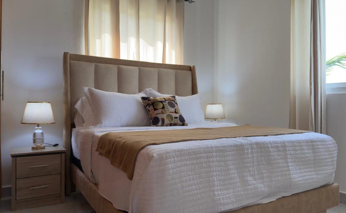 buyDRproperty Cozy bedroom with a king-size bed, white linens, and neutral decor. Sosua Real Estate