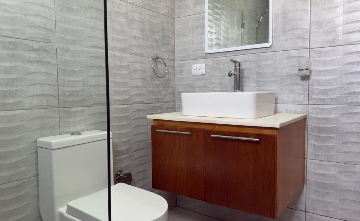 buyDRproperty Modern bathroom with gray wave tile, floating wood vanity, and white square sink. Sosua Real Estate