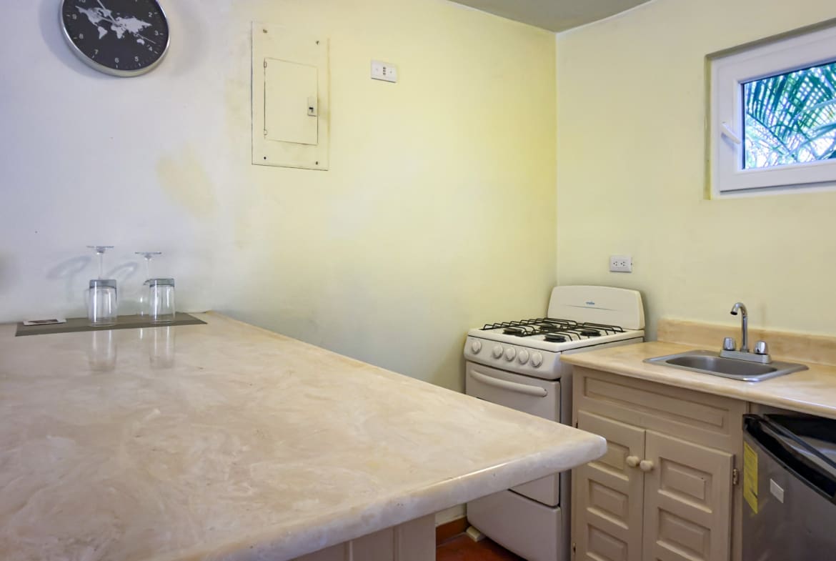 buyDRproperty Compact kitchen with a marble countertop, stove, sink, and small refrigerator. Sosua Real Estate