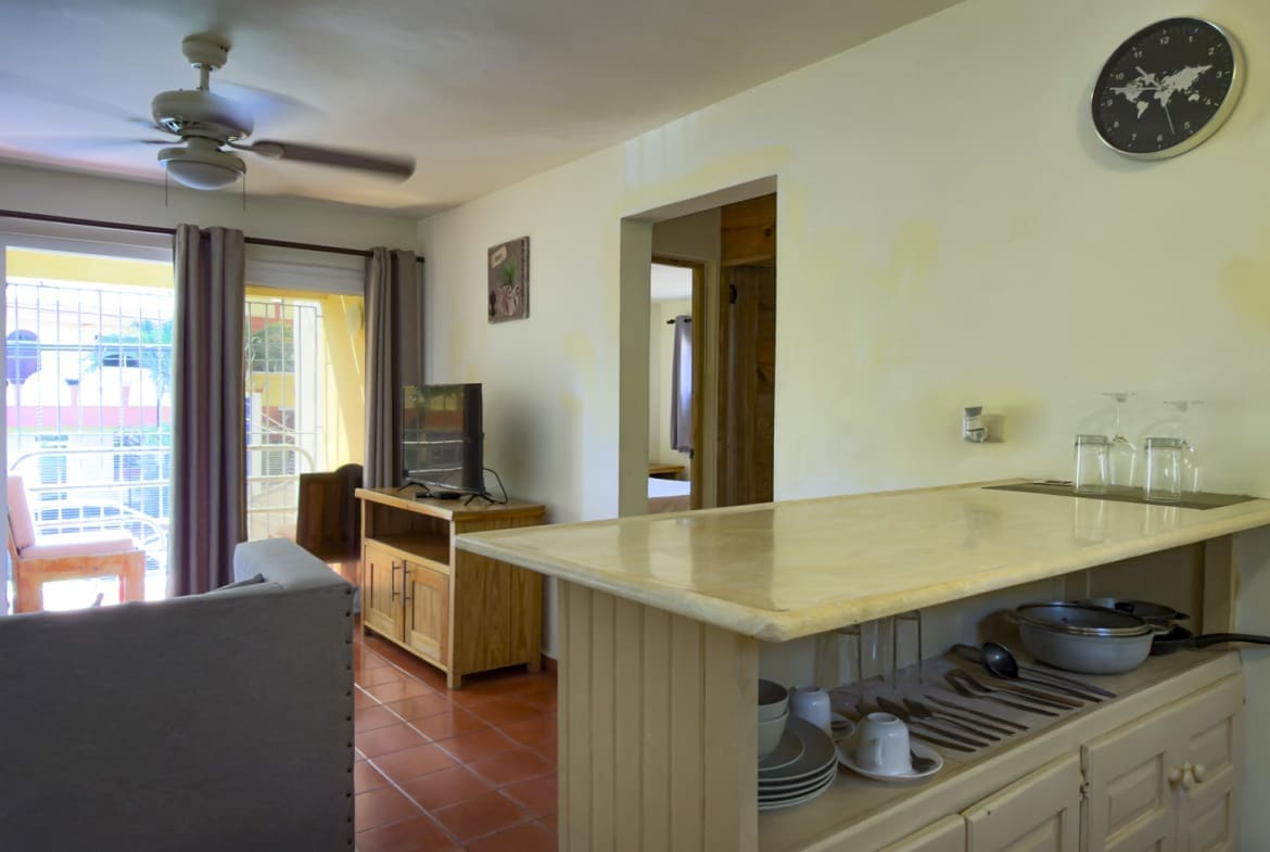 buyDRproperty Interior view of a modern apartment kitchen with a breakfast bar and living area. Sosua Real Estate
