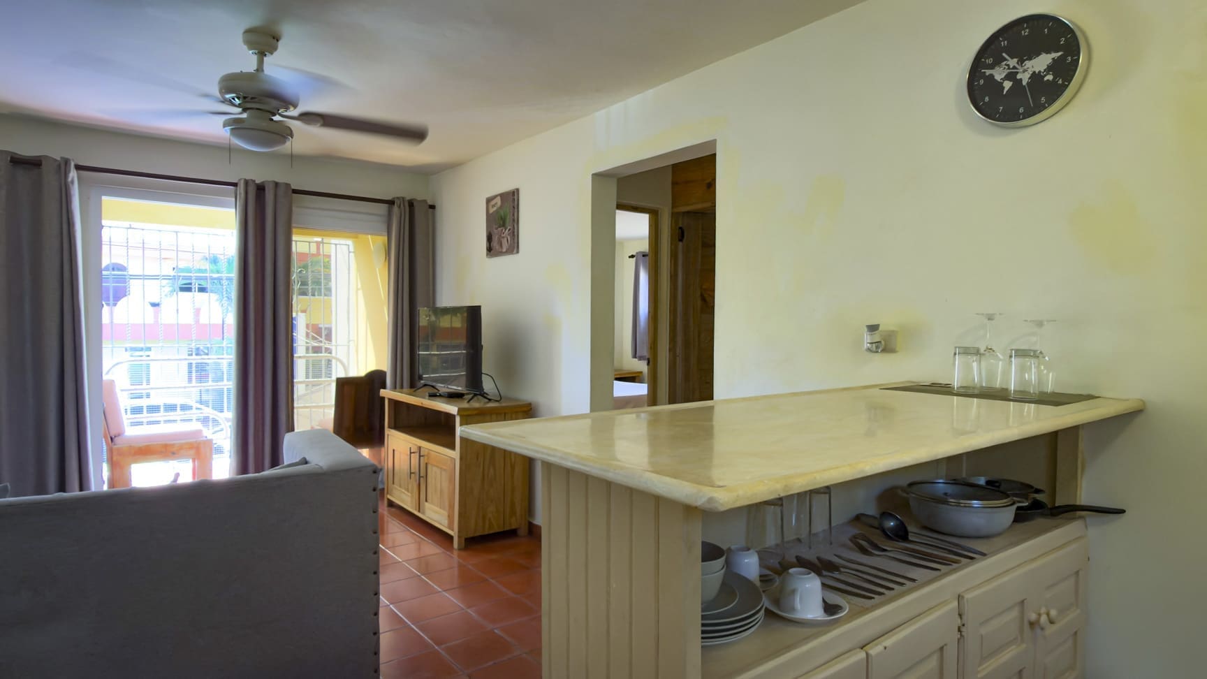 buyDRproperty Interior view of a modern apartment kitchen with a breakfast bar and living area. Sosua Real Estate
