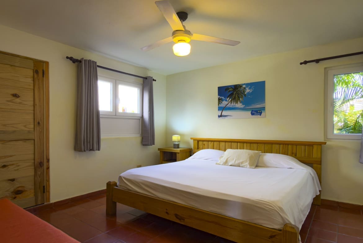 buyDRproperty Spacious bedroom with bed, nightstands, ceiling fan, and tropical painting Sosua Real Estate