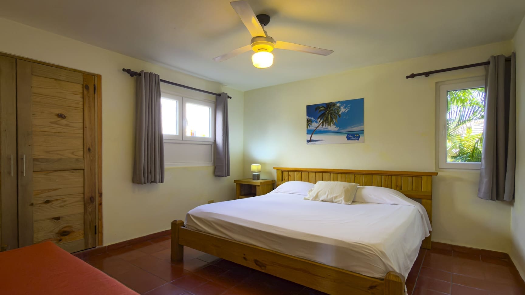 buyDRproperty Spacious bedroom with bed, nightstands, ceiling fan, and tropical painting Sosua Real Estate