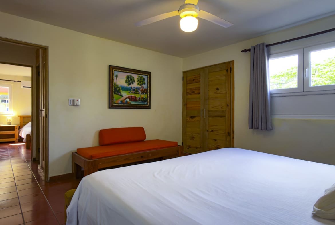 buyDRproperty Cozy bedroom with a large bed, wooden wardrobe, and a colorful painting. Sosua Real Estate
