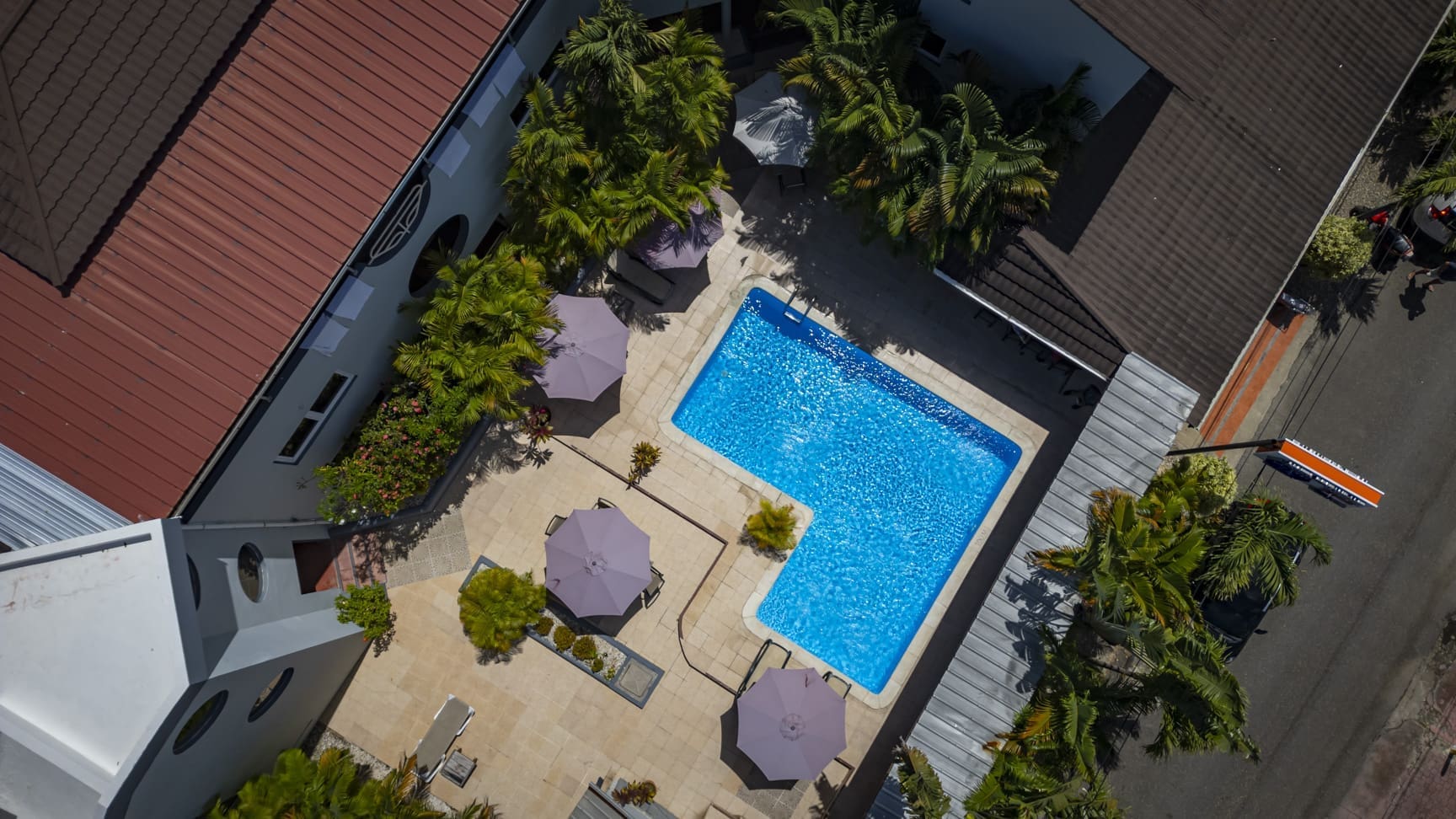 buyDRproperty Aerial view of a resort pool with lounge chairs and umbrellas, surrounded by palm trees. Sosua Real Estate