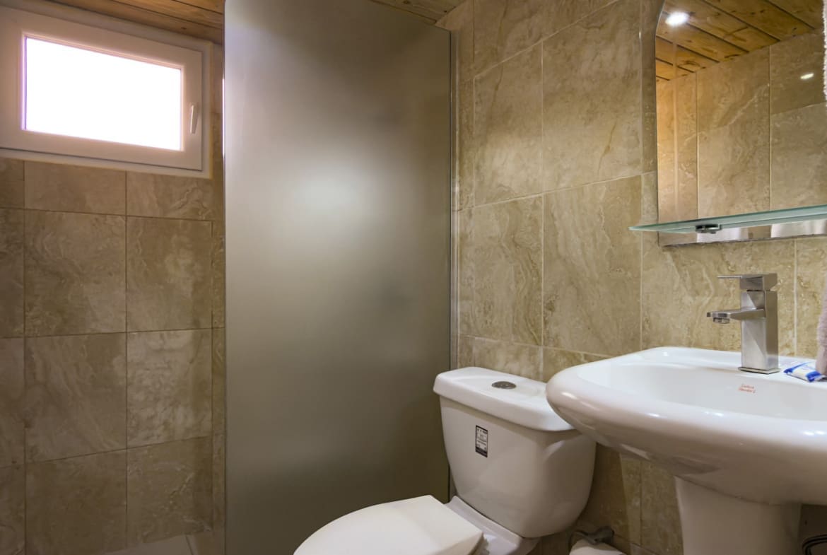 buyDRproperty Modern bathroom with a white toilet, sink, and frosted glass shower door. Sosua Real Estate