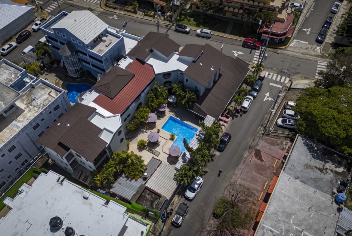 buyDRproperty Aerial view of a resort with a pool, palm trees, and surrounding buildings. Sosua Real Estate