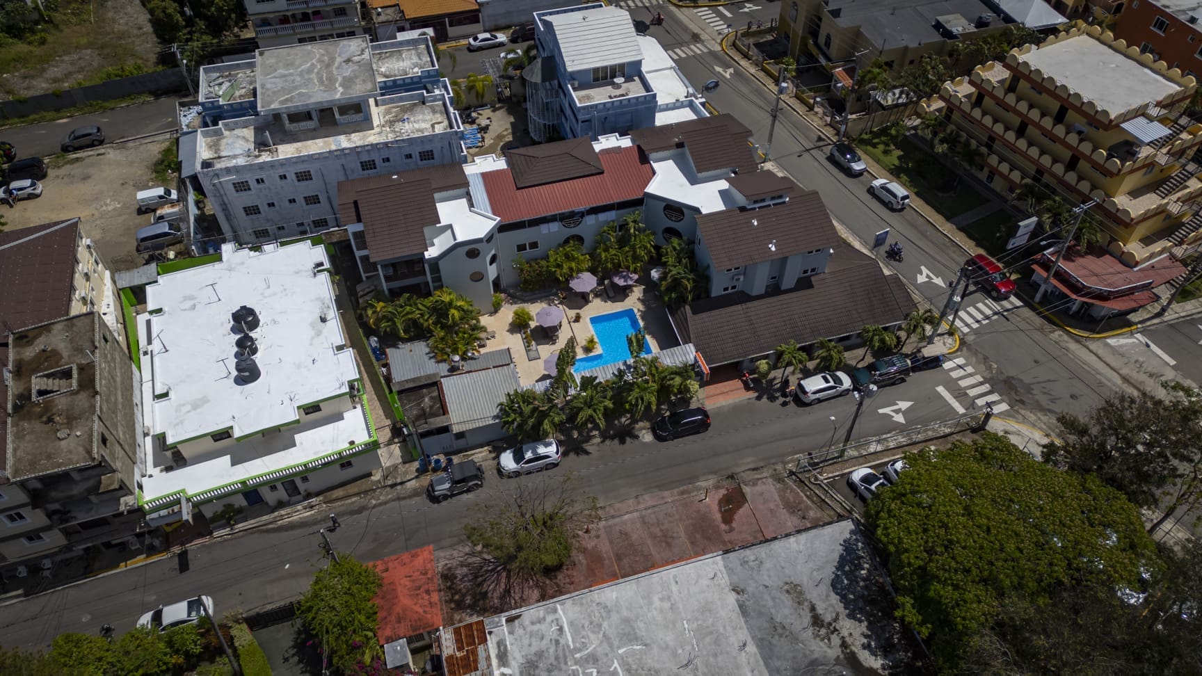 buyDRproperty Aerial view of a colorful Caribbean resort with a pool, surrounded by buildings and trees. Sosua Real Estate