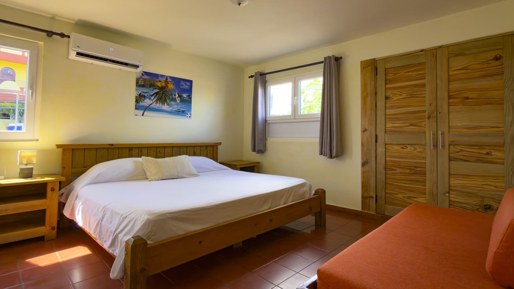 buyDRproperty Cozy bedroom with a king-size bed, wooden furniture, and tropical art. Sosua Real Estate