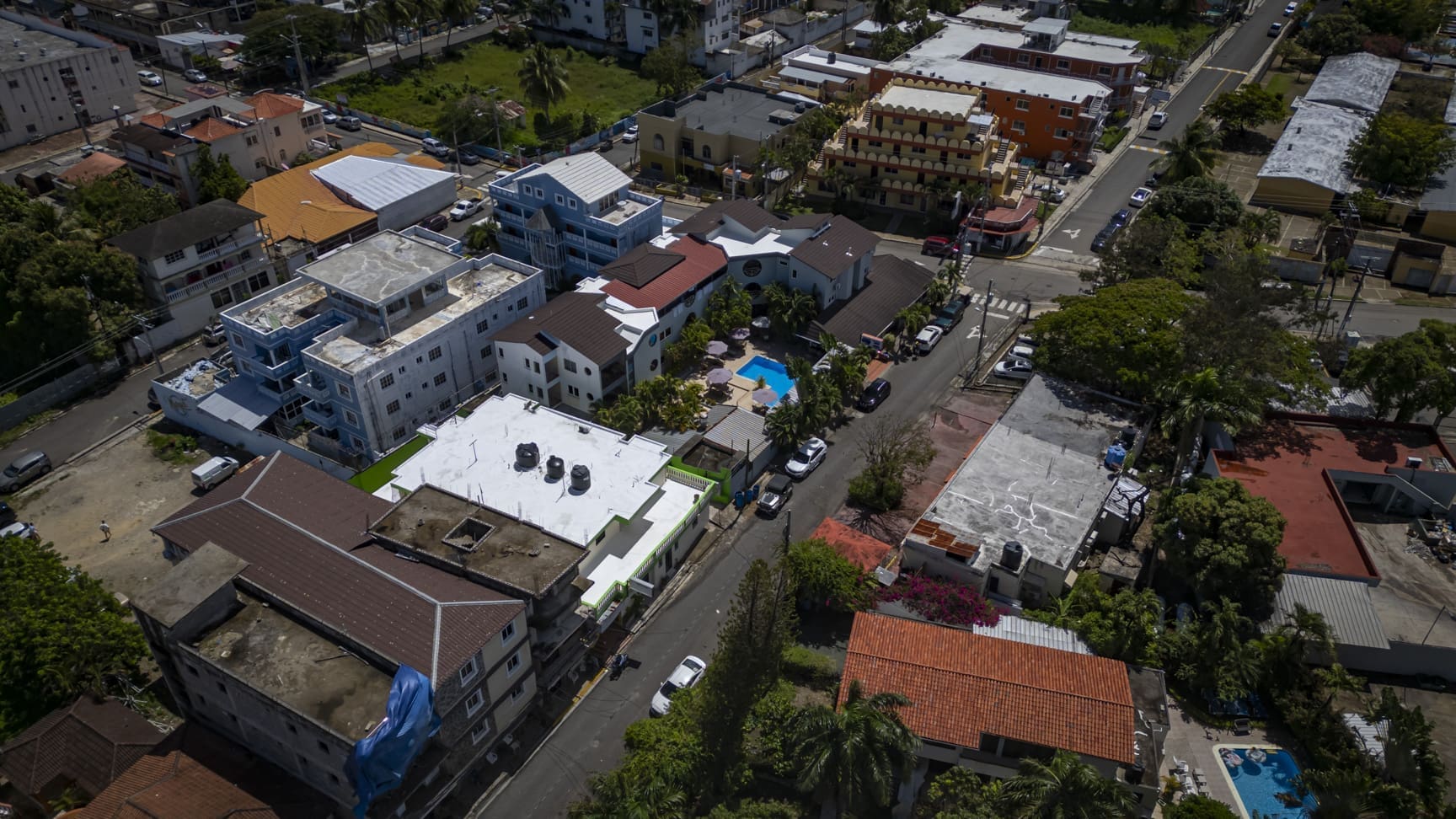 buyDRproperty Aerial view of a dense urban neighborhood with colorful buildings and palm trees. Sosua Real Estate