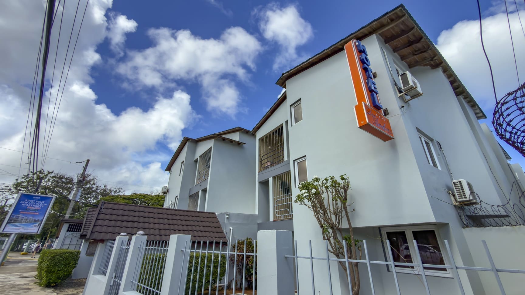 buyDRproperty Hotel building with bright blue sky and clouds, featuring a neon sign. Sosua Real Estate