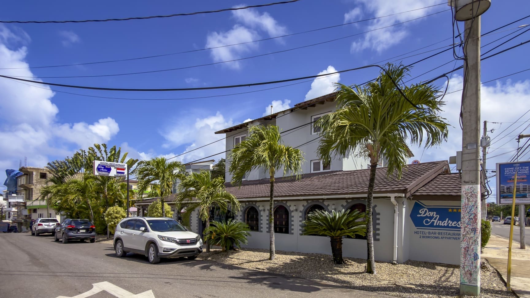 buyDRproperty Don Andres Hotel-Bar-Restaurant with palm trees and cars in front Sosua Real Estate
