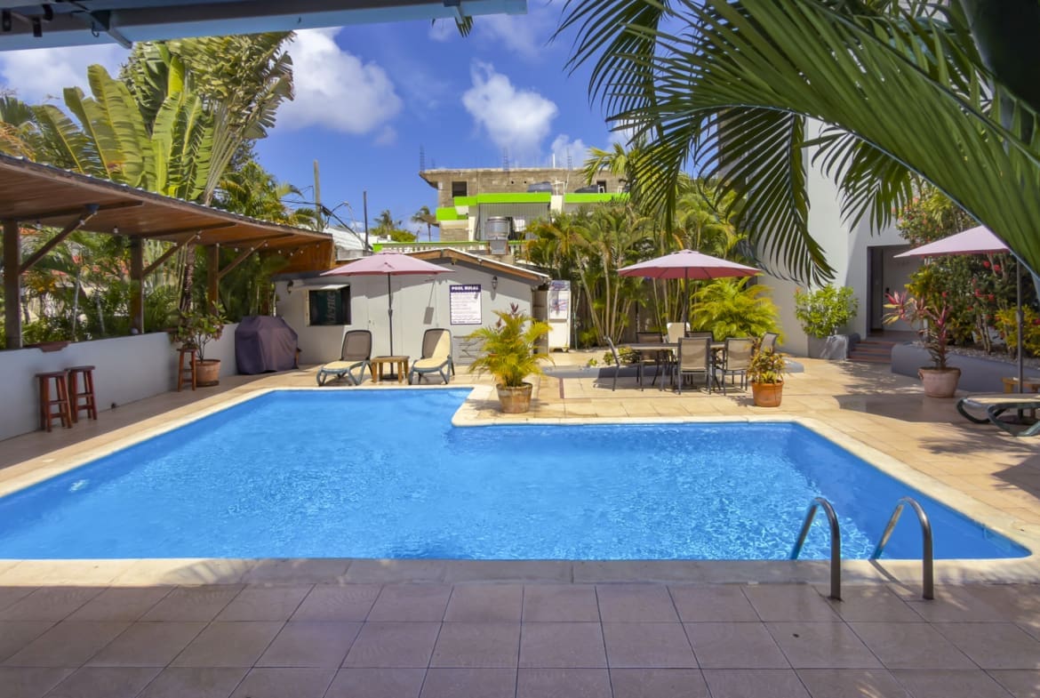 buyDRproperty Tropical resort pool with palm trees, lounge chairs, and umbrellas. Sosua Real Estate