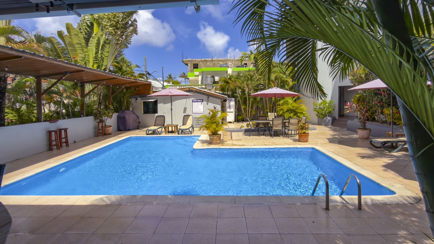 buyDRproperty Tropical resort pool with palm trees, lounge chairs, and umbrellas. Sosua Real Estate
