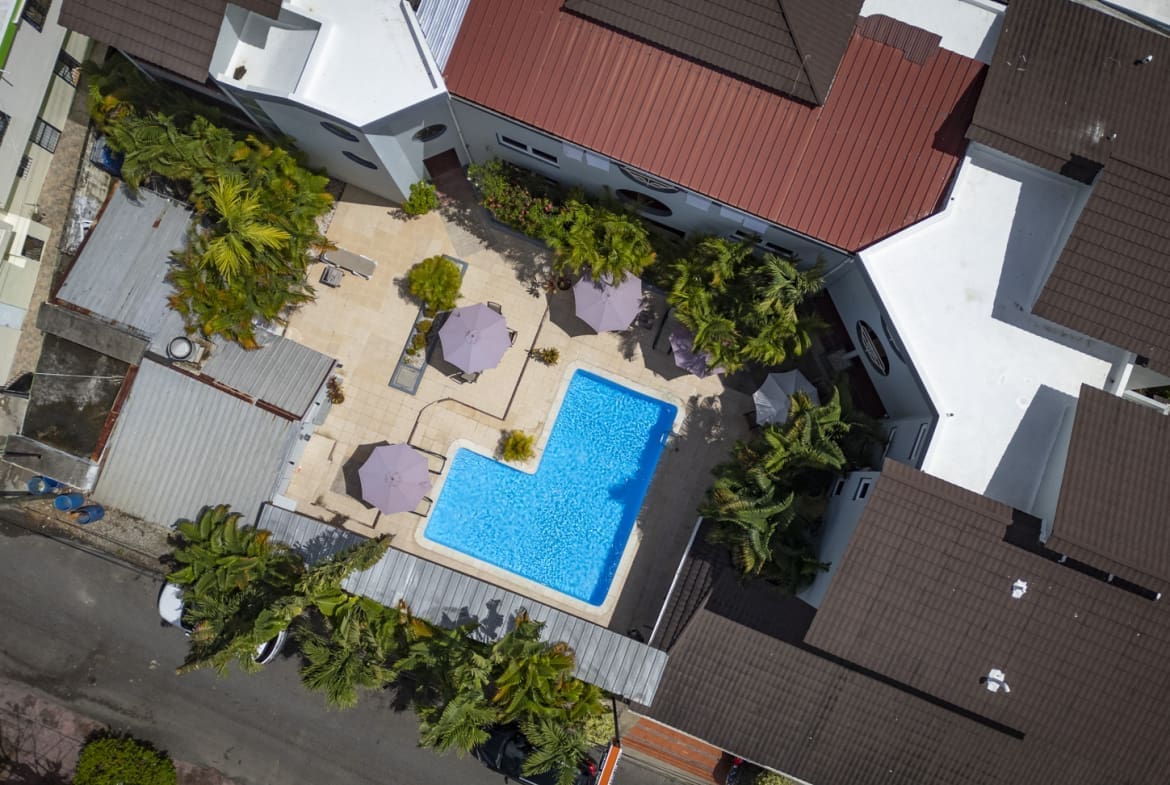 buyDRproperty Aerial view of a resort pool with lounge chairs and palm trees. Sosua Real Estate